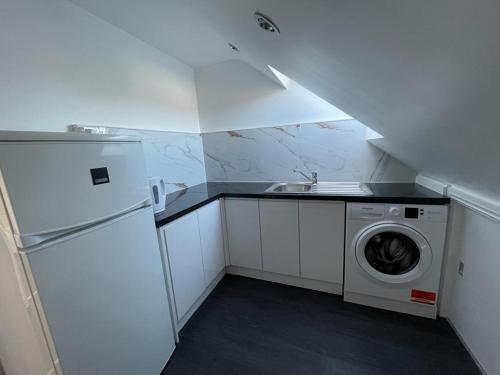 a small kitchen with a sink and a washing machine at Luxurious & Spacious Apartment with PARKING close to LONDON in Harold Wood