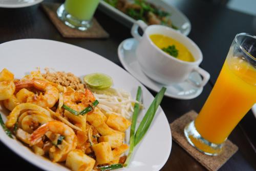 a plate of shrimp and noodles and a cup of orange juice at Coco View Hotel in Samut Songkhram