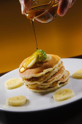 a person drizzling syrup onto a stack of pancakes at Coco View Hotel in Samut Songkhram