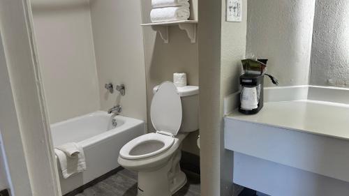 a white bathroom with a toilet and a bath tub at Days Inn by Wyndham San Diego Vista in Vista