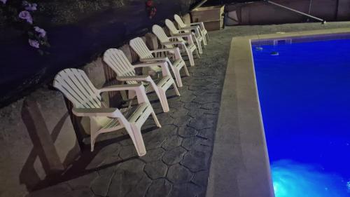 a row of white chairs next to a swimming pool at Chalet con piscina en escalona in Toledo