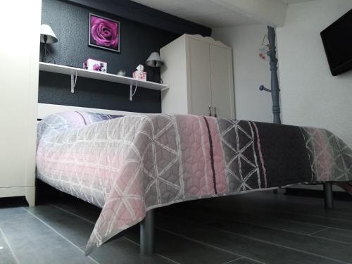 - une chambre avec un lit recouvert d'une couverture rose et grise dans l'établissement F1 avec piscine dans résidence privée, à Bagnols-en-Forêt