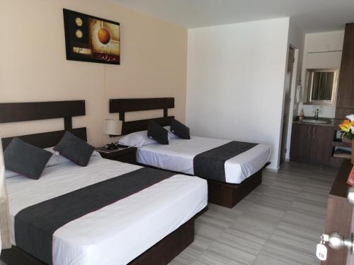 a hotel room with two beds and a kitchen at Hotel Quinta Las Fuentes Bernal in Bernal