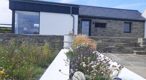 a stone house with a large window and a garden at Rose Meadow Lodge in Liscannor