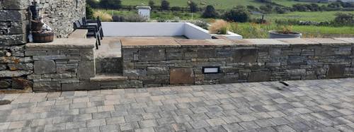 a stone retaining wall with a bench on a patio at Rose Meadow Lodge in Liscannor