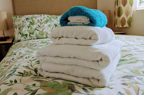 una pila de toallas sentadas encima de una cama en Oak Tree View - relax, reconnect, explore or work en East Harling