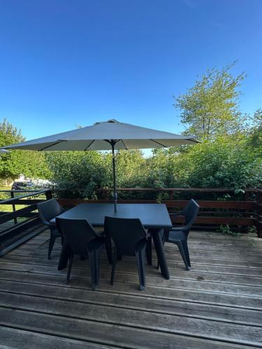 a table and chairs with an umbrella on a deck at Le petit Rabais in Virton