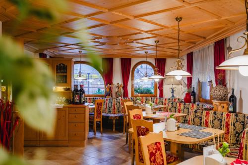 un restaurante con mesas, sillas y ventanas en Garni Hotel Belalp, en Santa Cristina Valgardena