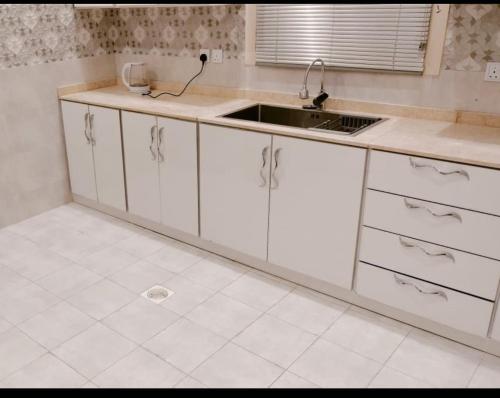 a kitchen with white cabinets and a sink at جوهرة البيعة للوحدات السكنية in Taif