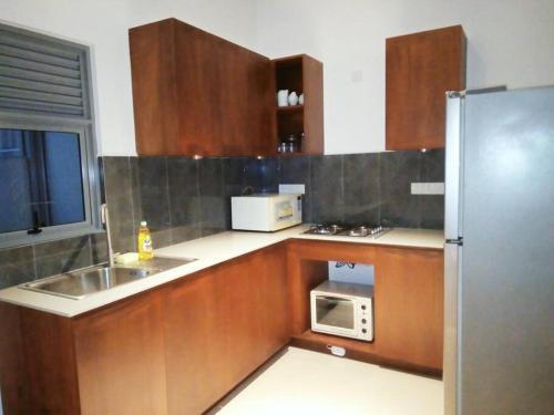 una cucina con armadi in legno, forno a microonde e frigorifero di 1F/F4/U4 ,Elixia 3C'S Apartments Malabe a Malabe