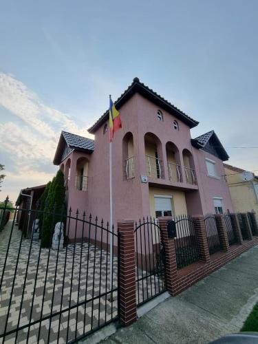 a pink house with a fence and a flag at Parnica Home in Dudeştii Noi
