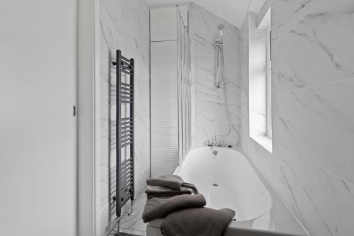 y baño blanco con bañera y toallas. en Modern 3-Bed Terraced House in Sutton-In-Ashfield en Skegby