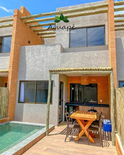 a patio with a table and chairs next to a swimming pool at Milagres Aguapé Beach House in São Miguel dos Milagres