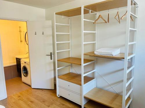 un armario blanco con estanterías de madera y una lavadora en Maison à 5 minutes de Paris et idéal Disneyland en Montreuil