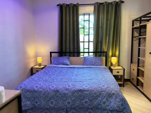 a bedroom with a bed with a blue comforter and a window at Villa Nducha in Dar es Salaam