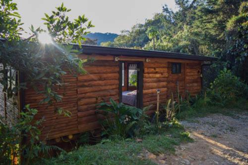 a log cabin with a door open in a forest at Glamping con jacuzzi cerca a Medellin in Guarne