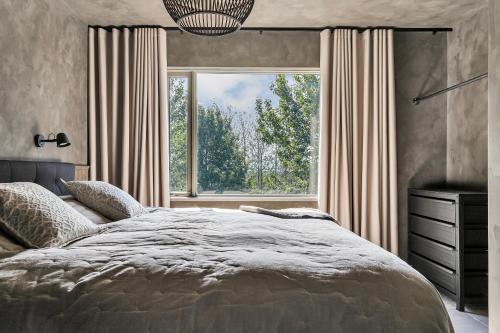 een slaapkamer met een groot bed en een groot raam bij Hvoll Villa in Ölfus