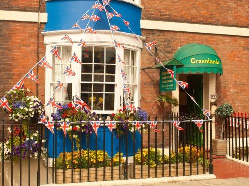 Un edificio con banderas británicas en una valla. en Greenlands Guest House, en Weymouth