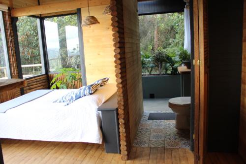 a bedroom with a bed and a bathroom with a toilet at Glamping con jacuzzi cerca a Medellin in Guarne