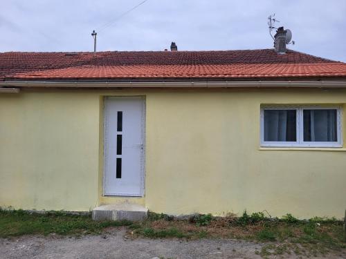 una casa amarilla con puerta blanca y techo rojo en Hamidani jkkld, en Aureilhan