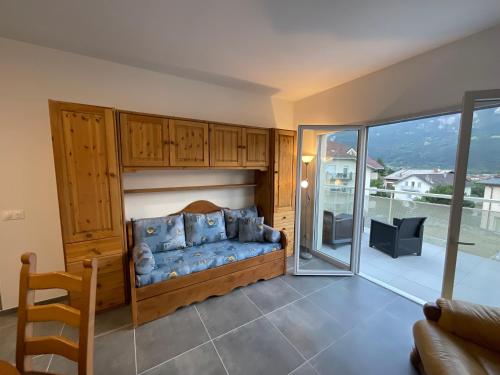 ein Wohnzimmer mit einem blauen Sofa und einem Balkon in der Unterkunft Appartement au pied du Mont-Blanc 2! in Sallanches