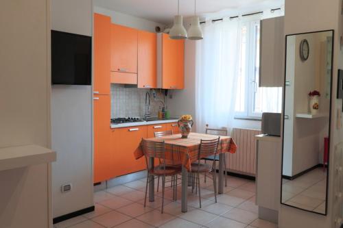 een keuken met oranje kasten en een tafel en stoelen bij Bilocale accogliente tra Como e Milano in Saronno