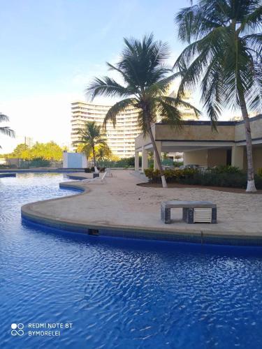 a swimming pool with palm trees in front of a building at Margarita & More, Omas in Porlamar