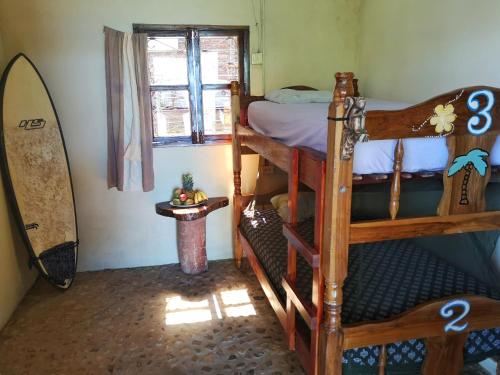 a bedroom with two bunk beds and a surfboard at Monkey House Hostel in Tola