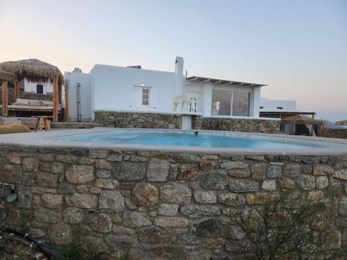 a villa with a swimming pool in front of a stone wall at Diamond Of Mykonos in Ano Mera