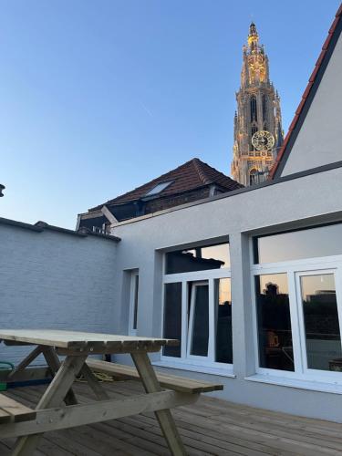 a picnic table in front of a building with a clock tower at Rooftop apartment with 60m terrace overlooking the cathedral in Antwerp