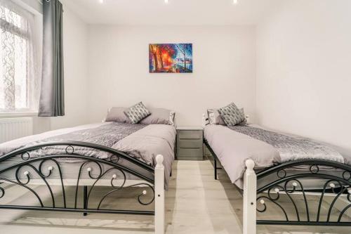 dos camas sentadas una al lado de la otra en un dormitorio en Stylish 2Bedroom flat near train station in London, en Seven Kings