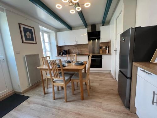 une cuisine avec une table, des chaises et un réfrigérateur dans l'établissement Le Phare du Bout du Monde - Logement proche du port, à La Flotte