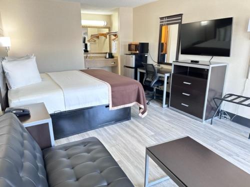 a hotel room with a bed and a flat screen tv at Deluxe Inn - Fayetteville I-95 in Fayetteville