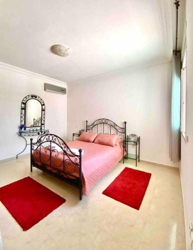 a bedroom with a bed and two red rugs at Hayriad : Charmant 3 Chambres . Wifi, Smart TV in Rabat