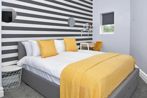 1 dormitorio con 1 cama con pared a rayas en One Battison - Affordable Rooms, Suites & Studios in Stoke on Trent, en Stoke on Trent