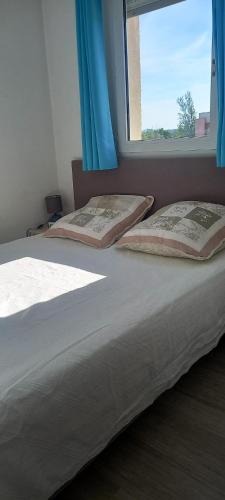 - un lit avec deux oreillers et une fenêtre dans l'établissement Appartement accueillant à Mandelieu-la-Napoule 32 m² avec balcon, à Mandelieu-la-Napoule