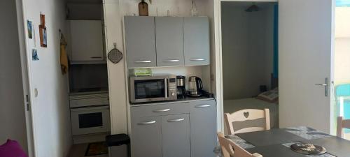 une petite cuisine avec un micro-ondes et une table dans l'établissement Appartement accueillant à Mandelieu-la-Napoule 32 m² avec balcon, à Mandelieu-la-Napoule