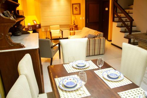 uma sala de jantar com uma mesa com pratos e copos de vinho em Casa Felice - Canela em Canela