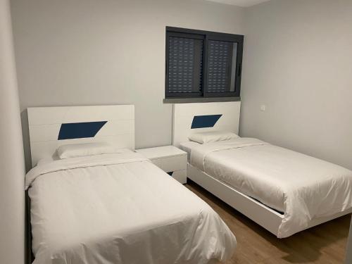 two beds in a small room with white walls at Paradise Garajau in Garajau