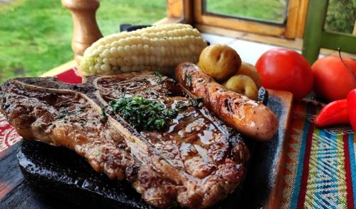a steak and sausages and corn on a table at Ruta de los volcanes in Machachi