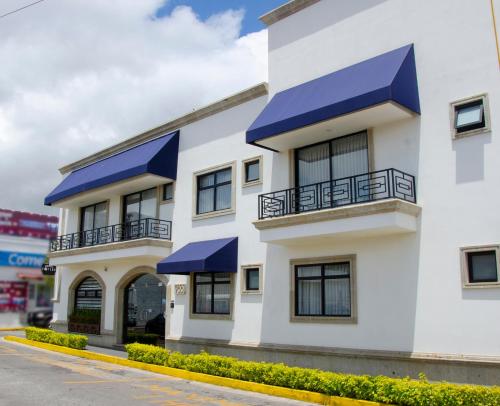 a white building with blue awnings on it at Hotel Esfera Tulancingo in Tulancingo