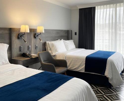 una camera d'albergo con 2 letti e una scrivania con sedia di Hotel Esfera Tulancingo a Tulancingo