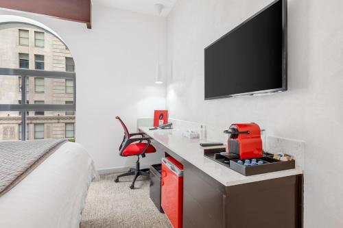 a bedroom with a desk with a tv on a wall at The O Hotel, Trademark Collection by Wyndham in Los Angeles