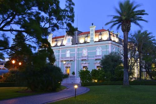 a large white house with a palm tree in front of it at Pestana Palace Lisboa Hotel & National Monument - The Leading Hotels of the World in Lisbon