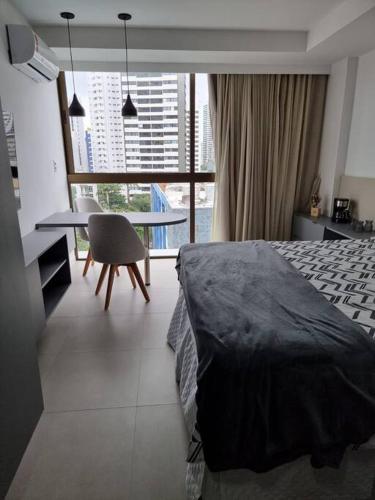 a bedroom with a bed and a table with a chair at Flat em Boa Viagem 100% Equipado in Recife