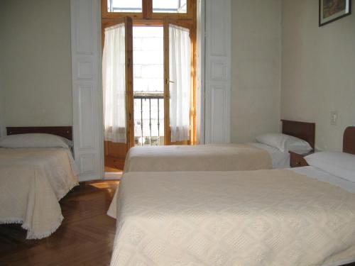 two beds in a room with a window at Hostal Tudescos in Madrid