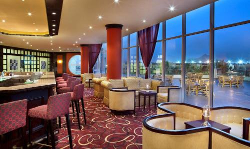 DoubleTree by Hilton Sharks Bay Resort في شرم الشيخ: مطعم بطاولات وكراسي ونوافذ كبيرة