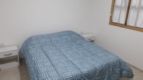 a bedroom with a bed with a blue and white bedspread at Cabaña La Escondida in Trelew