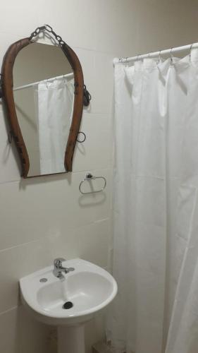 a white bathroom with a sink and a mirror at Cabaña La Escondida in Trelew