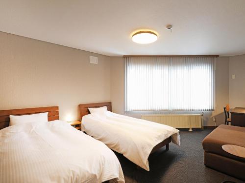 a hotel room with two beds and a window at RONENAI BASE in Biei